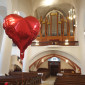 Großer roter Luftballon in Herzform vor der Orgel